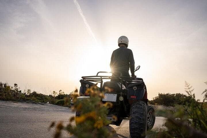 Quad bike on a Gozo trail at sunset with a rider in a helmet.