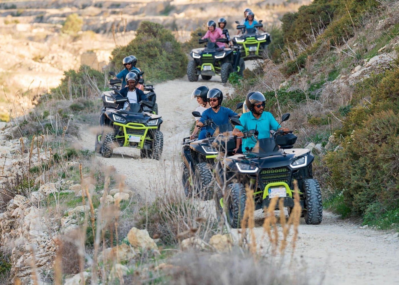 Self-drive quad convoy on a winding Gozo dirt trail with lime-green ATVs.
